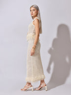 Woman wearing a white crochet dress against a plain background