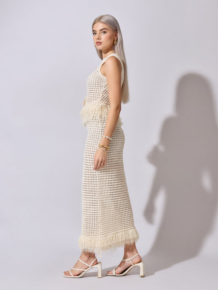 Woman wearing a white crochet dress against a plain background