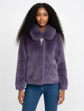 Woman wearing a purple textured jacket with a fur collar on a white background