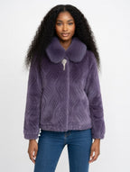 Woman wearing a purple textured jacket with a fur collar on a white background