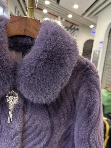 Purple fur coat with a brooch on a hanger in an indoor setting