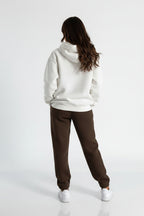 Person wearing a white hoodie and brown pants on a white background