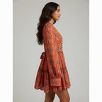 Woman wearing a patterned orange dress against a plain background