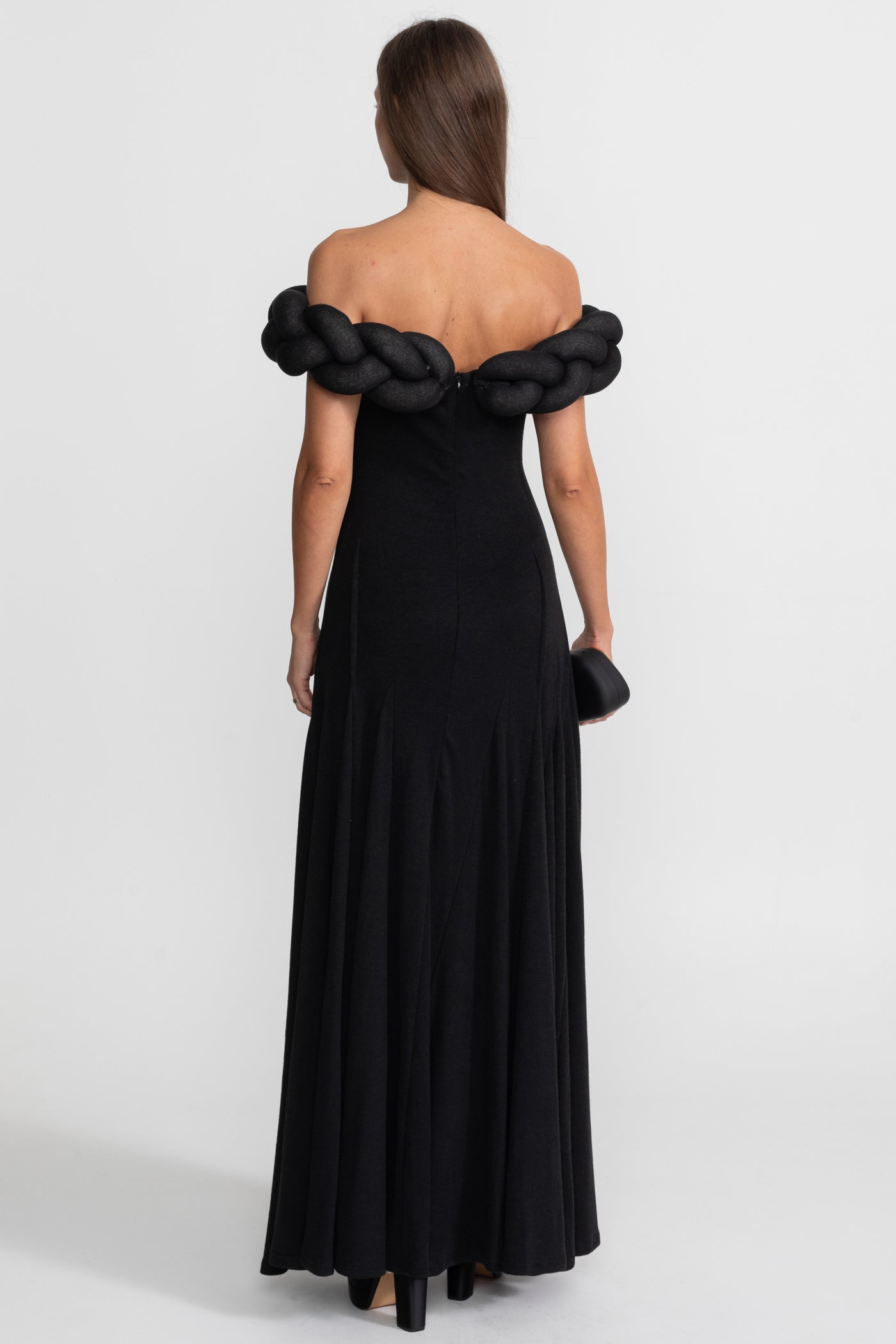 Black off-shoulder evening gown with braided detailing on a white background