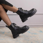 Black studded combat boots worn with fishnet stockings on a neutral background