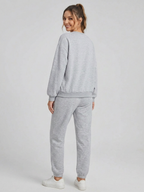 Woman wearing a gray sweatshirt and pants set on a white background