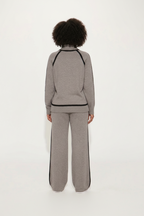 Person wearing a gray tracksuit with black trim on a white background