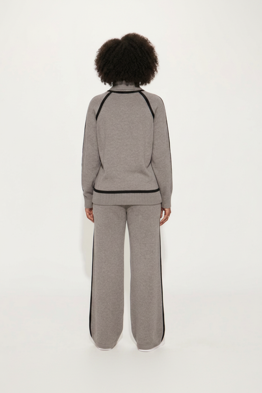 Person wearing a gray tracksuit with black trim on a white background