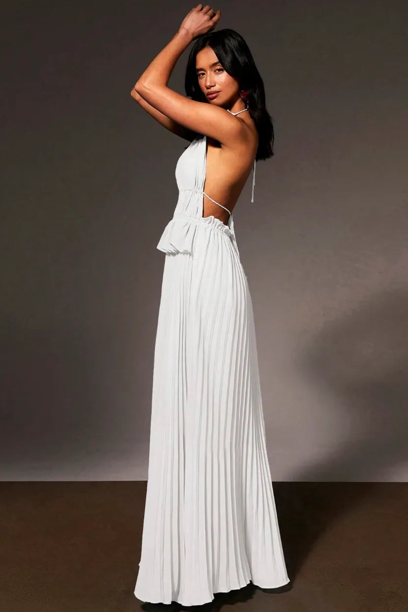 A woman modeling a floor-length white halter gown with side cutouts and a pleated skirt, posed against a dark gray studio background.