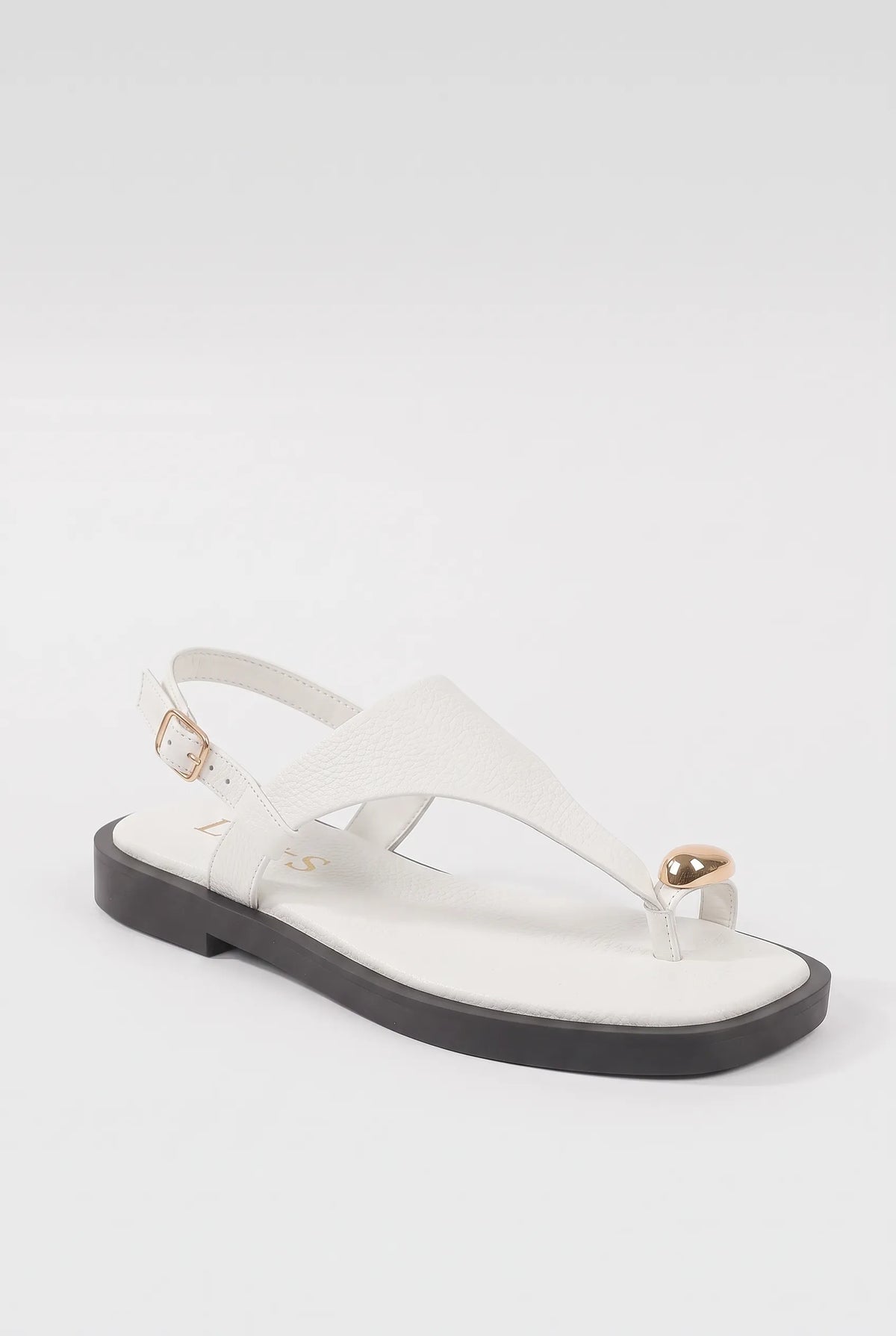 A white leather thong sandal with a low black platform sole and a small gold-tone decorative accent on the toe post, shown against a light gray background.