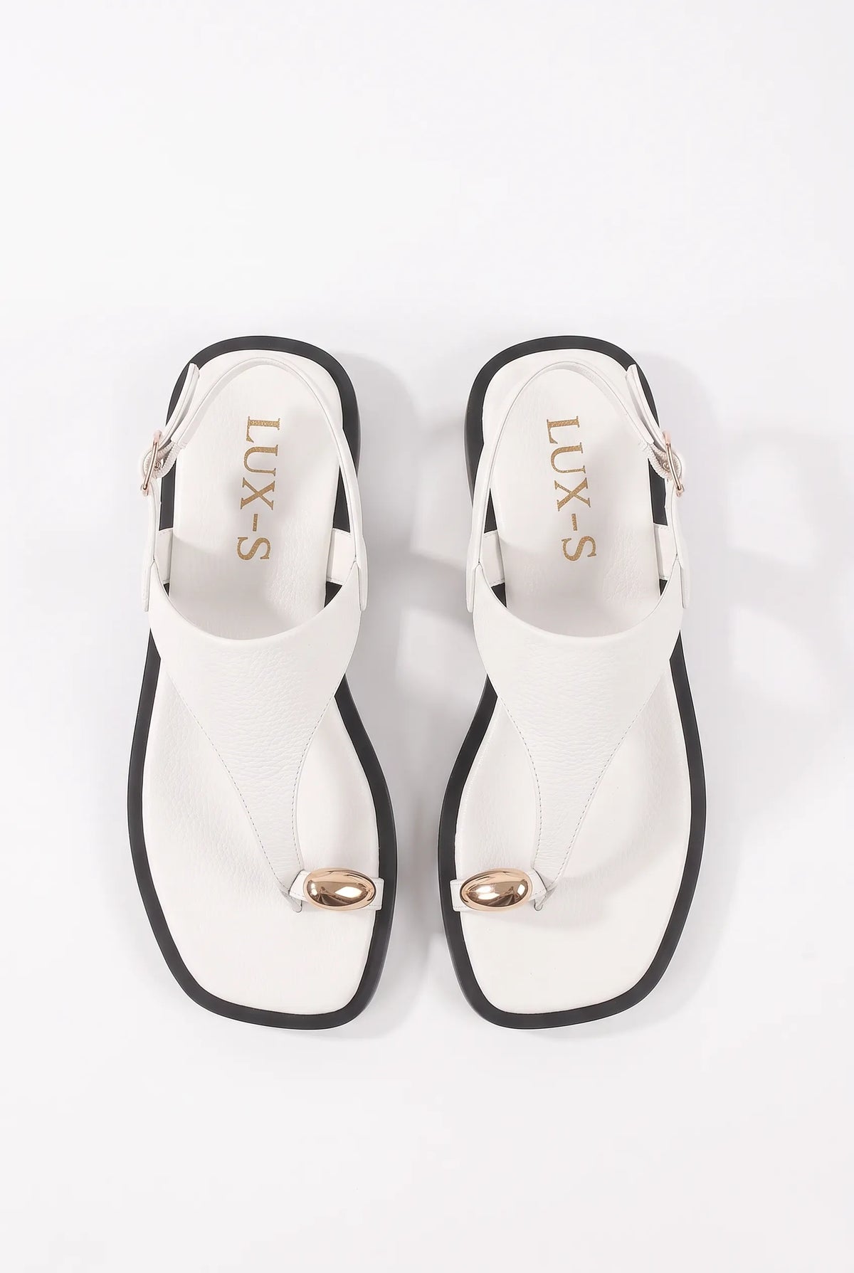 A pair of white thong sandals with black trim and metallic gold accents, shown from a top-down view on a white background. The brand name 'LUX-S' is printed on the insole.