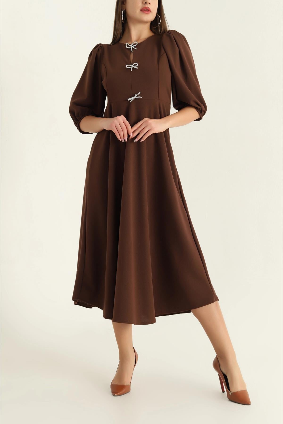 Woman wearing a brown dress with puff sleeves on a white background