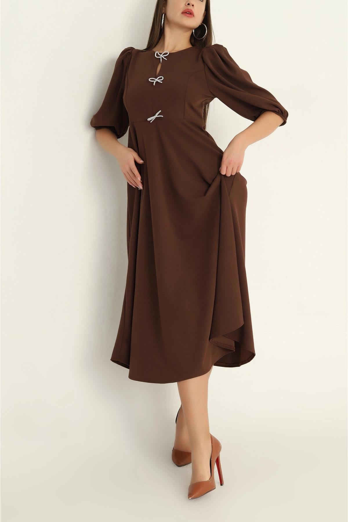 Woman wearing a brown dress with puff sleeves against a white background