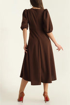 Brown dress with puff sleeves worn by a person on a white background