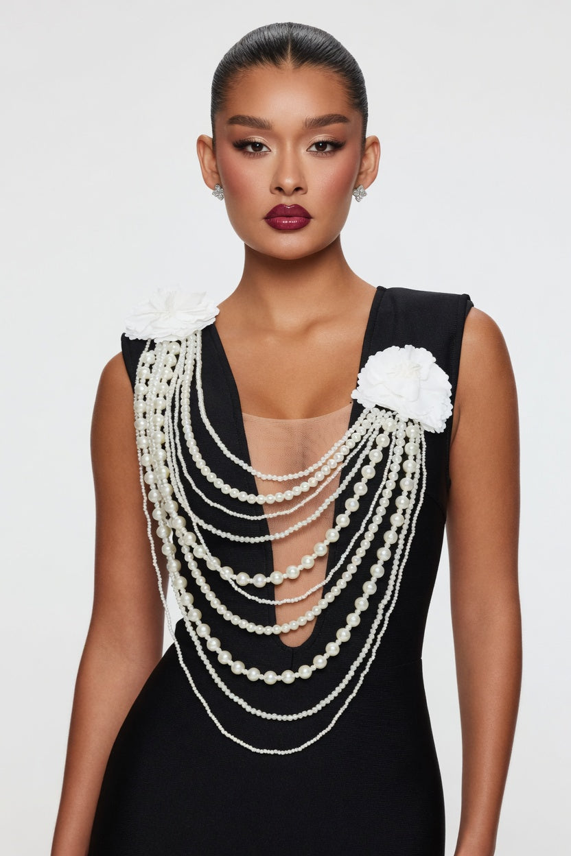 Woman wearing a black dress with pearl embellishments on a white background