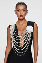 Woman wearing a black dress with pearl embellishments on a white background